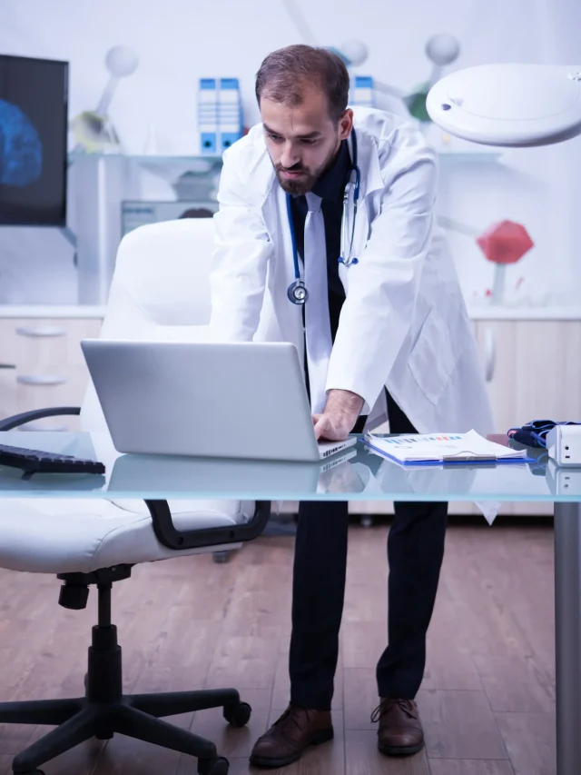 full-lenght-portrait-handsome-doctor-working-his-laptop-hospital-cabinet-doctor-laboratory